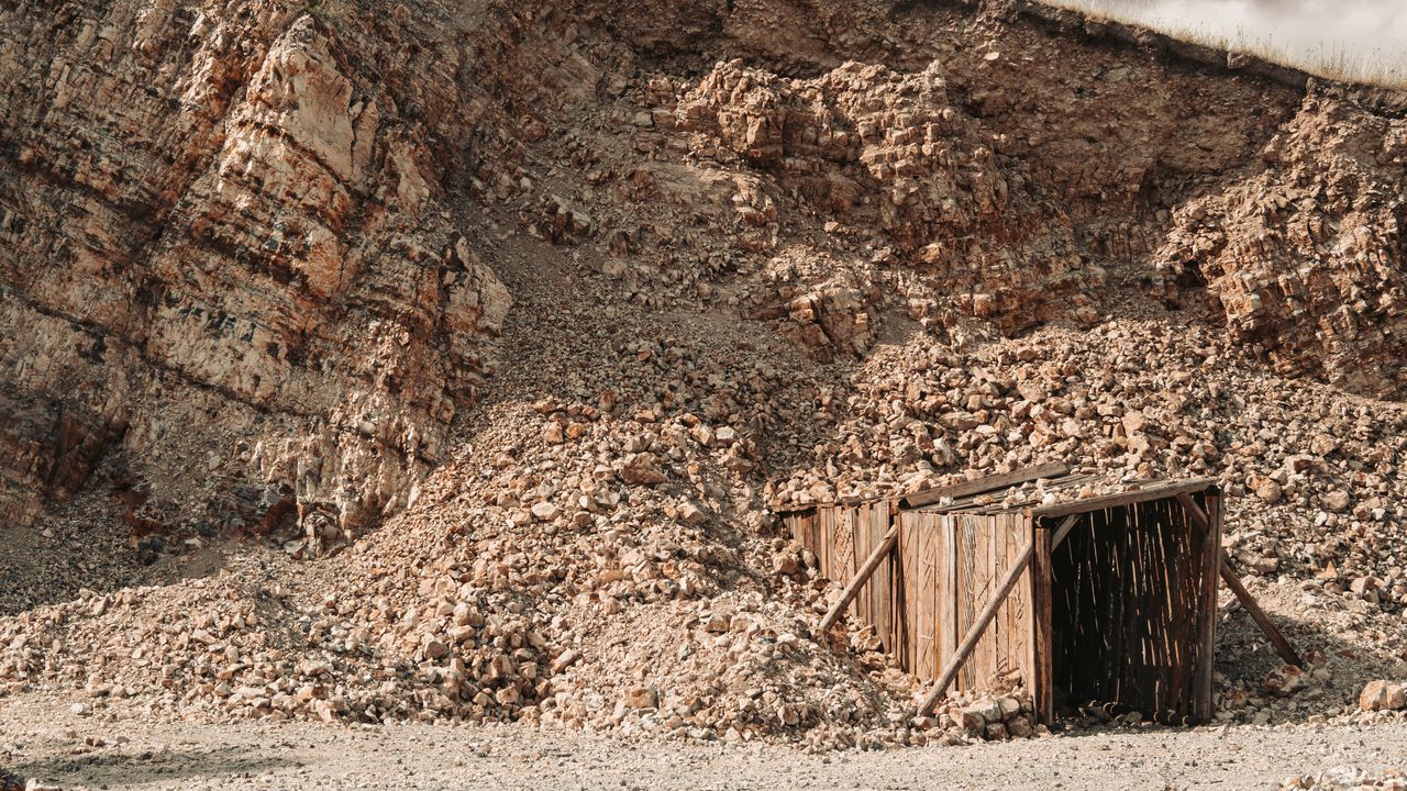 ours-journey Weathered wooden entrance amidst rocky terrain of an old mine.
